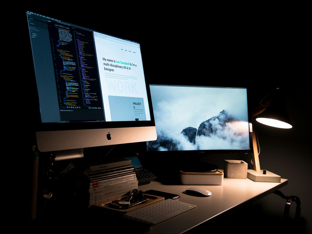 A workspace at night with a code editor and a website design open on screen